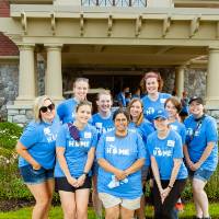 Alumni pose in front of the Alumni House